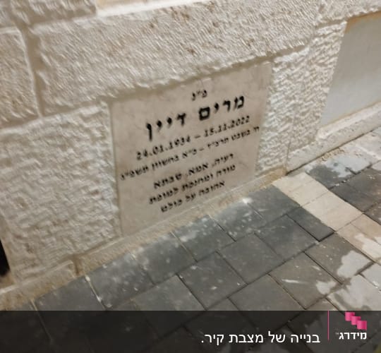 מצבה עם כיתוב בעברית על קיר אבן